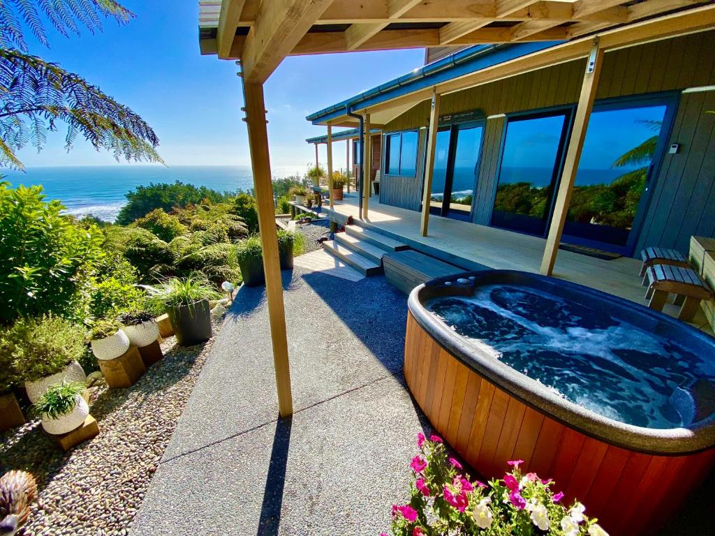 a hot tub on a porch of a house at Tasman Sea Retreat in Punakaiki