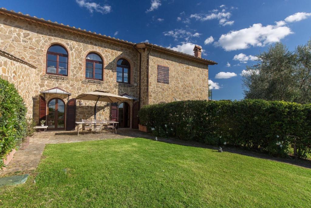 a large brick house with a lawn in front of it at Appartamento Il Nido Di Giulia in Asciano