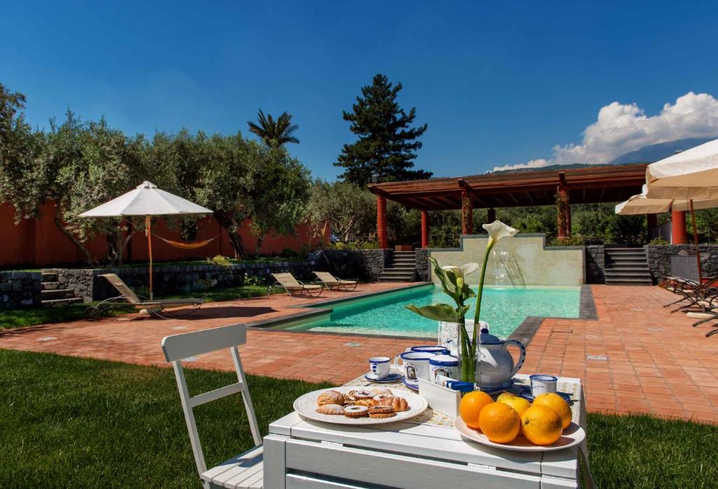 uma mesa com pratos de fruta ao lado de uma piscina em Apartment in Linguaglossa/Sizilien 38037 em Linguaglossa