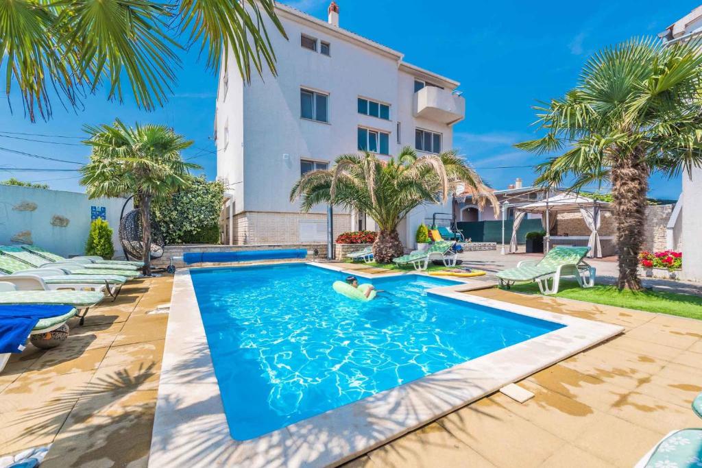 - une piscine en face d'une maison avec des palmiers dans l'établissement Apartments in Sukosan/Zadar Riviera 7897, à Sukošan