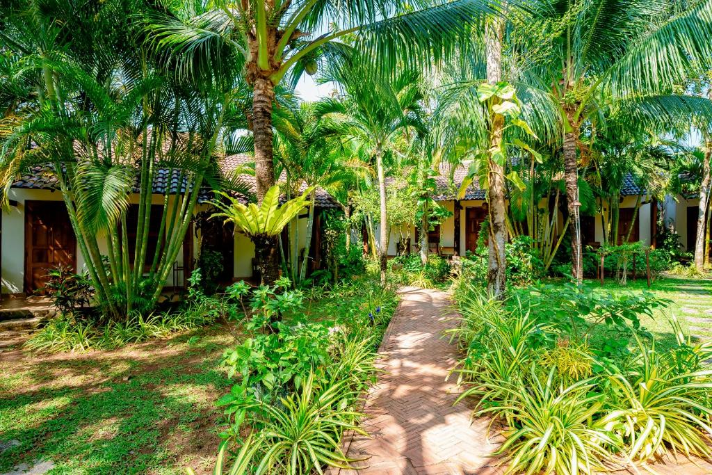 a path in front of a house with palm trees at La Mer Resort, Phú Quốc in Phú Quốc
