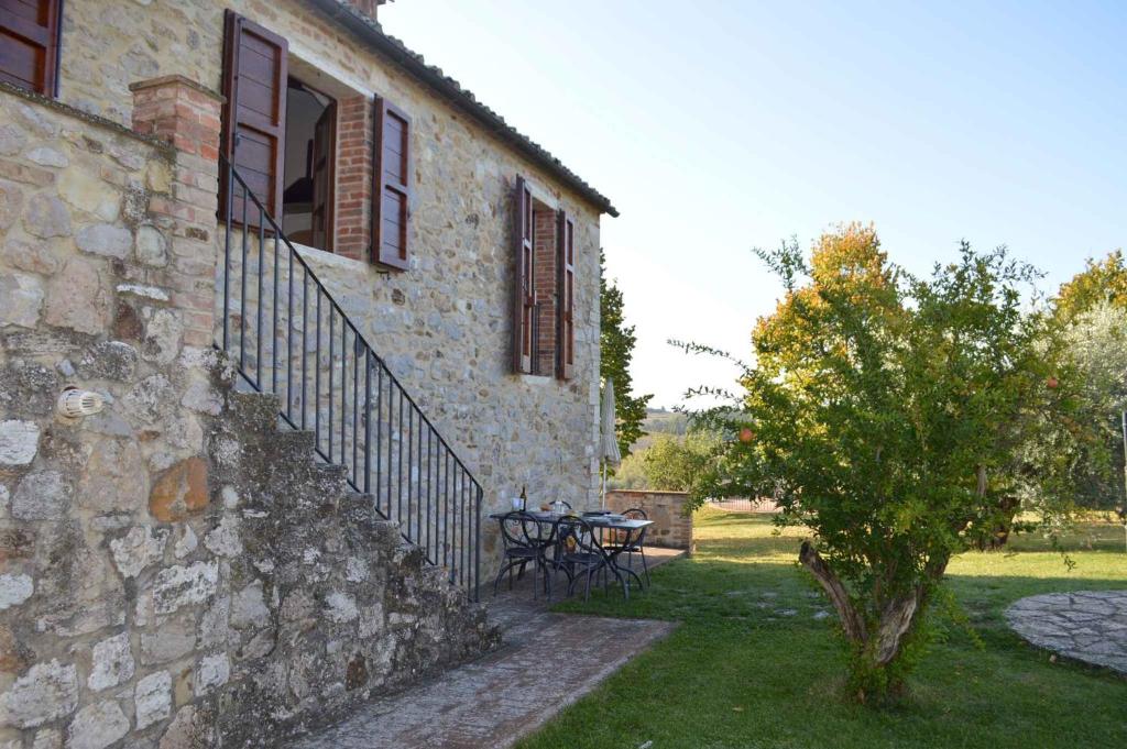 a stone building with a table and a tree next to it at Apartments in Asciano/Toskana 24096 in Serre di Rapolano
