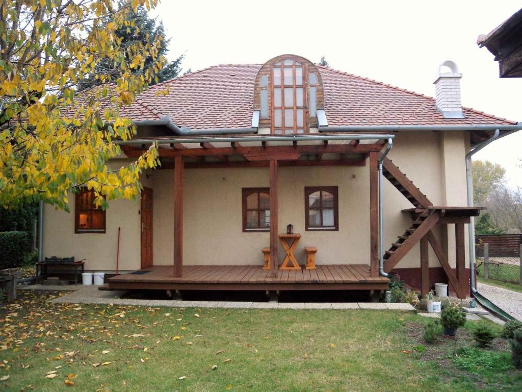 una pequeña casa con una gran terraza de madera en Holiday home in Balatonvilagos 31292, en Balatonvilágos