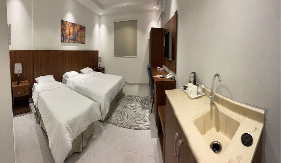 a hotel room with two beds and a sink at فندق كنان سويت in Sulţānah