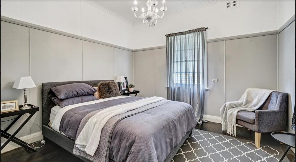a bedroom with a large bed and a chair at "Donnelly House" in Tenterfield