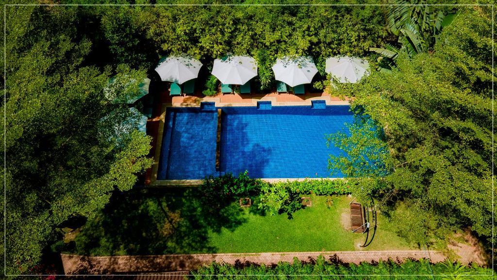 einen Blick über einen Pool in einem Garten mit Bäumen in der Unterkunft La Mer Resort, Phú Quốc in Phu Quoc