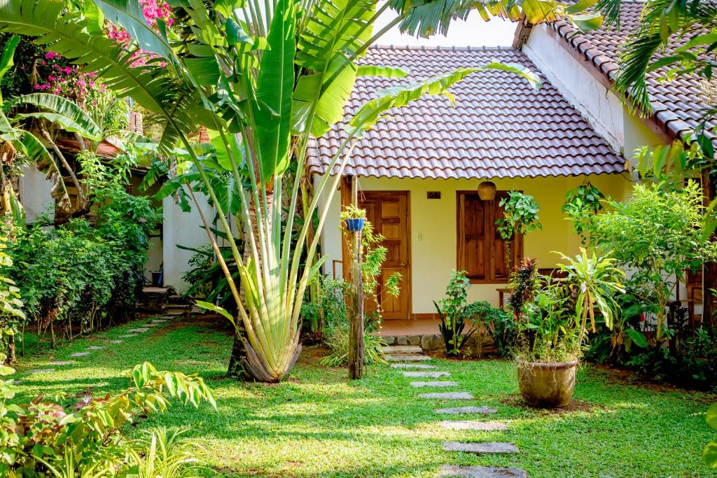 a garden with a house with a palm tree at La Mer Resort, Phú Quốc in Phú Quốc