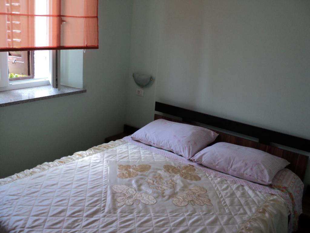 Un dormitorio con una cama con almohadas rosas y una ventana en Apartment Mandrač, en Novigrad Istria