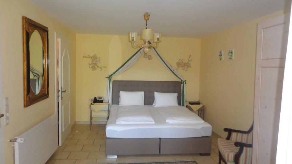 a bedroom with a bed and a chandelier at Hotel Restaurant - Häuserl im Wald Graz in Graz