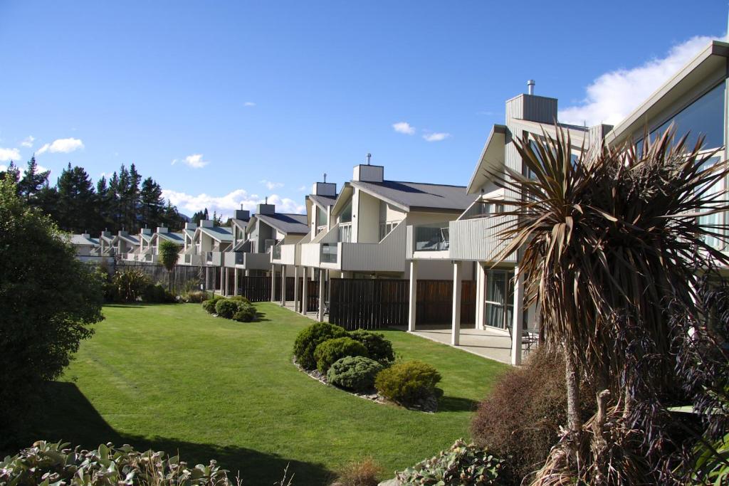 una fila de casas en un patio con césped verde en Distinction Wanaka Alpine Resort, en Wanaka