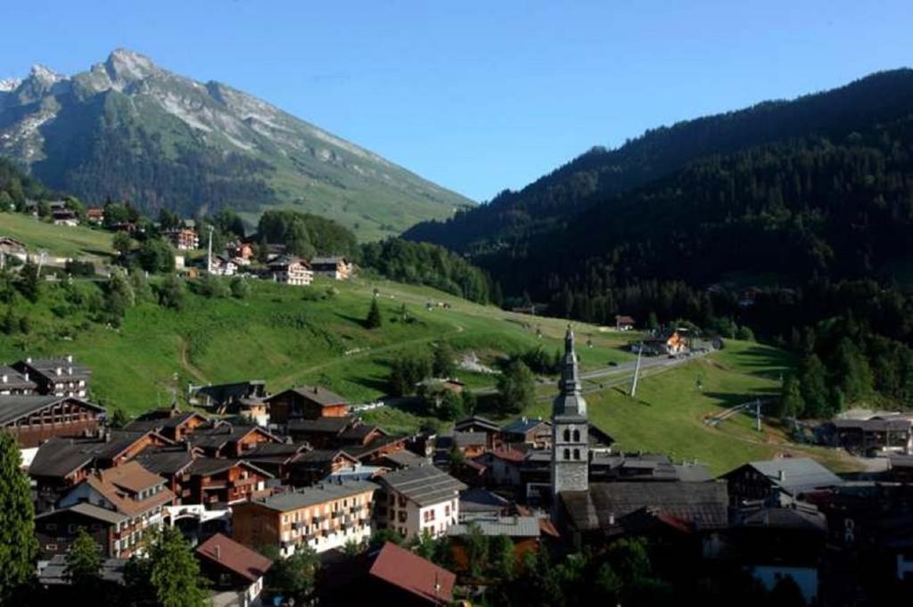 a small town with a church and a mountain at Résidence - Les Grandes Alpes in La Clusaz