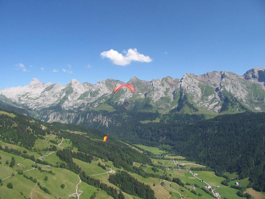 a person flying a kite over a valley with mountains at Résidence - Les Grandes Alpes in La Clusaz