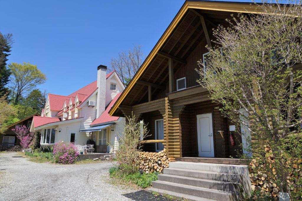 a house with a wooden roof and a driveway at Cottage&Pension Love Thirty in Karuizawa