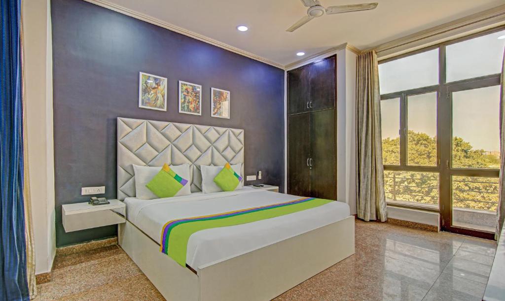 a bedroom with a large bed and a large window at Itsy By Treebo - City Centre Noida in Noida