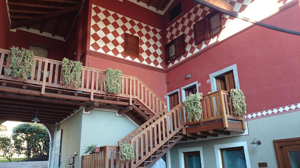 ein rotes Gebäude mit Holzbalkonen und Topfpflanzen in der Unterkunft Case Vacanze ai Burattini in Adrara San Rocco
