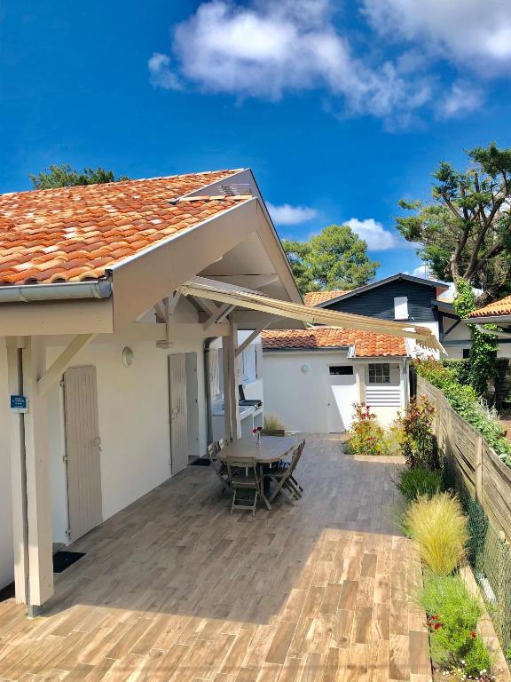 une terrasse avec une table et une maison dans l'établissement Villa La Plage Pour 7 Personnes A Proximite Du Port De Plaisance, à Capbreton