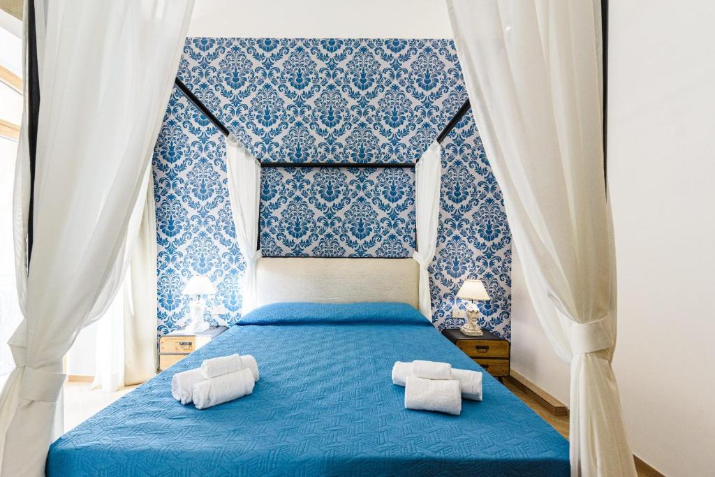 a blue bed with two white towels on it at Incao Holiday I Pupi House in Cefalù
