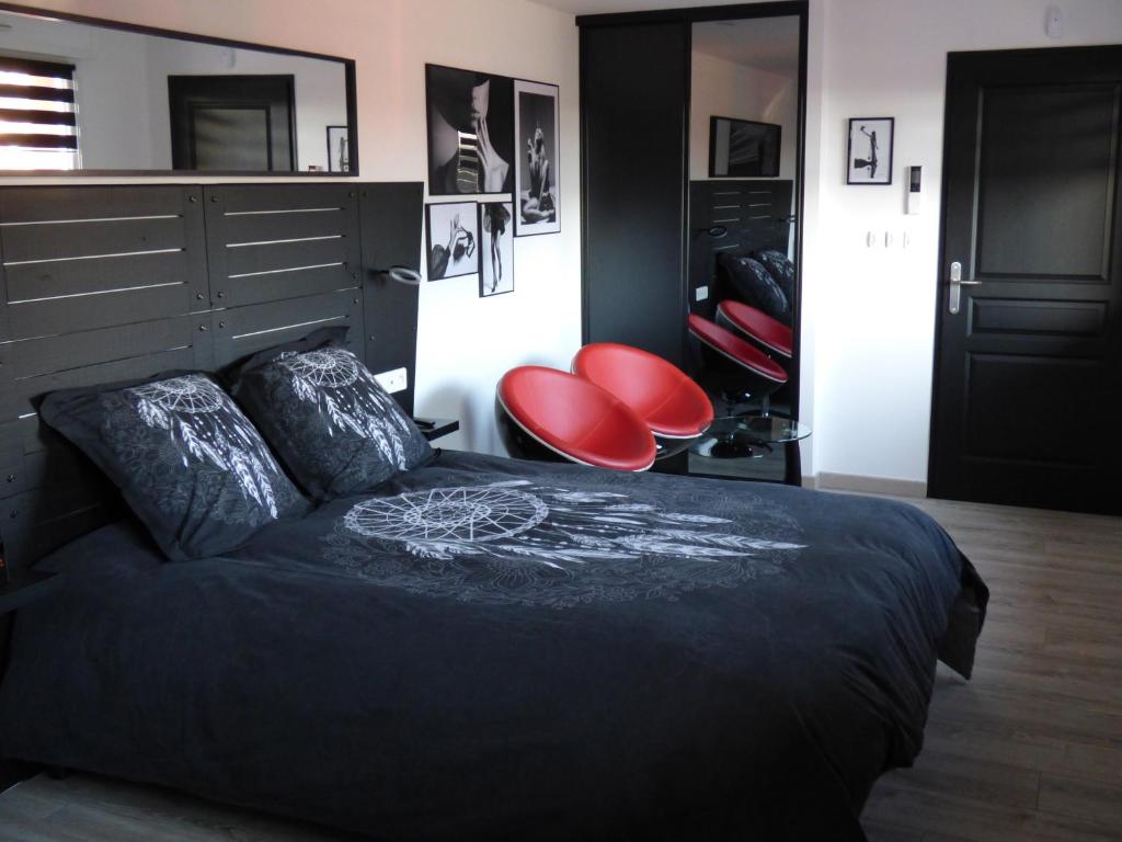 a bedroom with a bed and two red chairs at La Colline aux Yeux Doubs in Baume-les-Dames