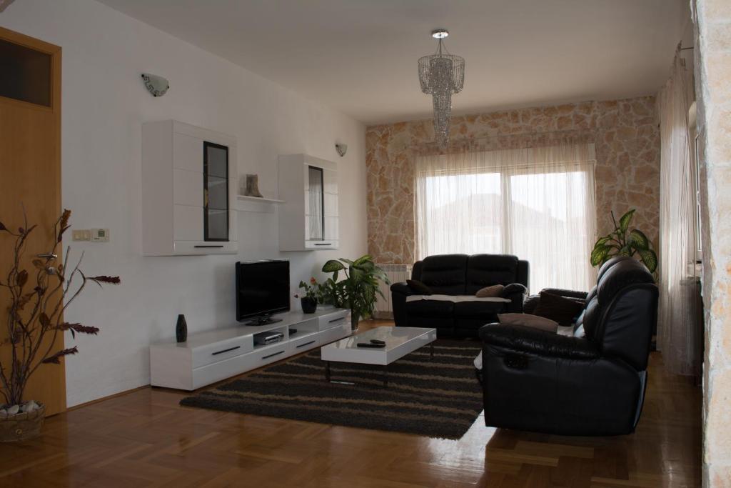 特羅吉爾的住宿－阿德里安娜公寓，客厅配有两把椅子和电视