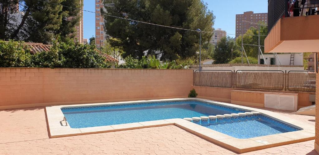 a swimming pool in a backyard with a brick wall at FMM Apartamentos Magic Finestrat Benidorm Holidays in Cala de Finestrat