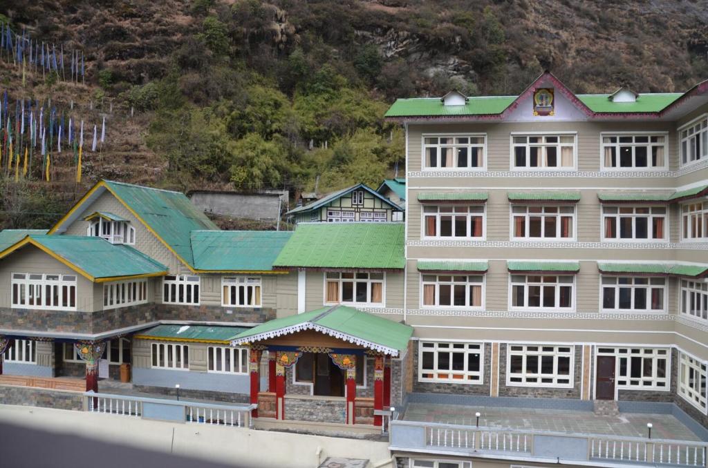 拉沖的住宿－Le Coxy Resort Lachung，山前有绿色屋顶的大建筑