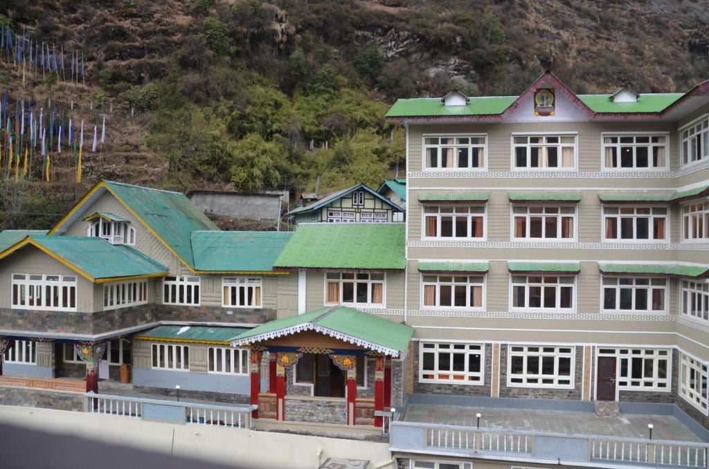 a large building with green roofs in front of a mountain at Le Coxy Resort Lachung in Lachung