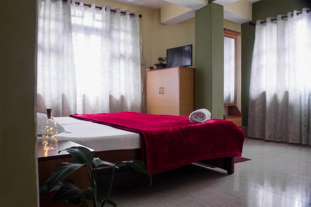 - une chambre avec un lit et une couverture rouge dans l'établissement Ashraya Boutique Homestay, à Rongli