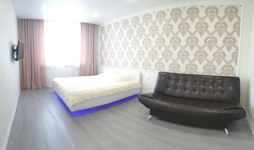 ヤロスラヴリにあるApartment on 8 Marta 17Aのベッドルーム(黒い革張りの椅子、ベッド付)