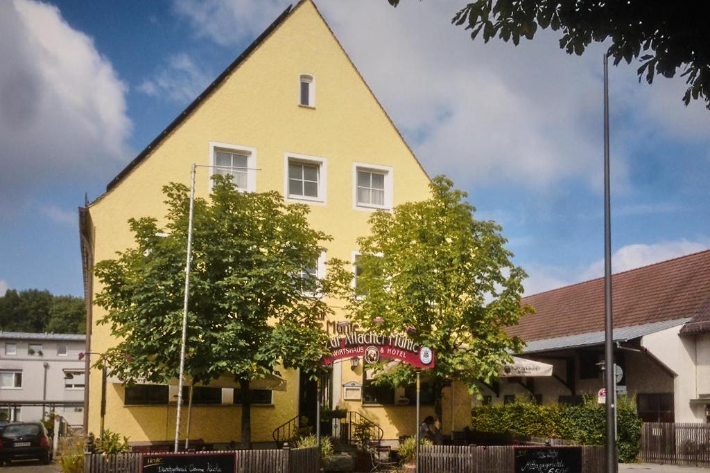 un bâtiment jaune avec un toit pointu dans l'établissement Zur Allacher Mühle, à Munich