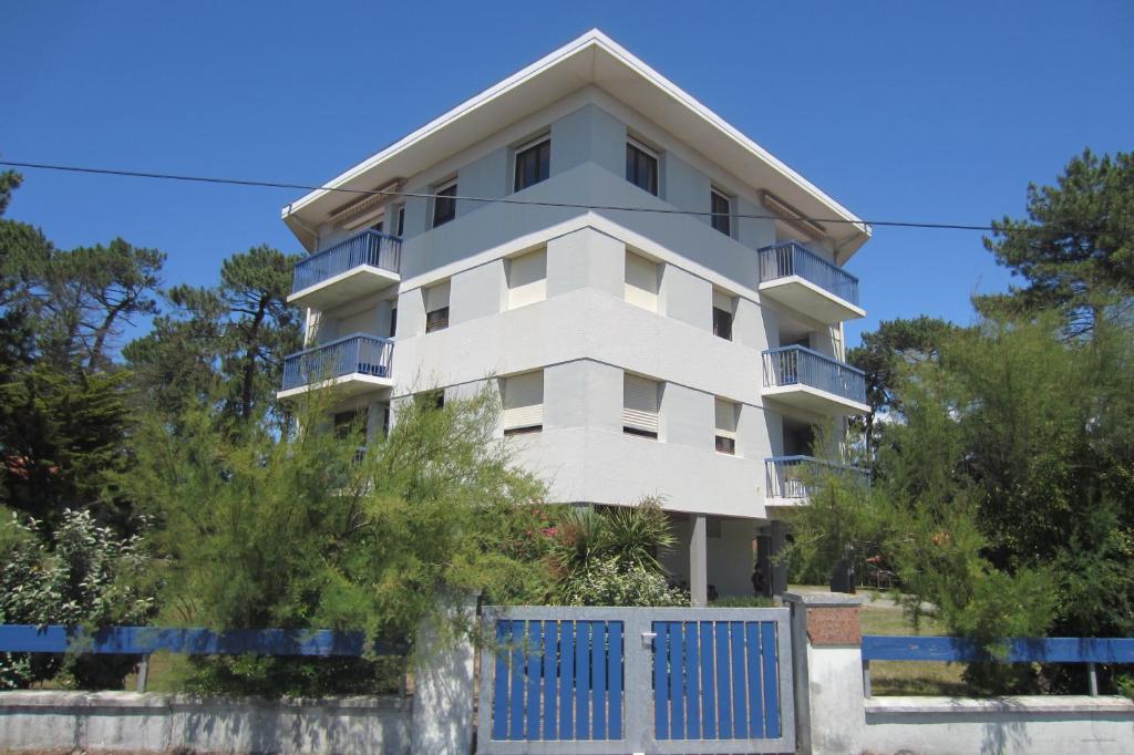 een wit appartementencomplex met een blauw hek bij Appartement Pour 2 Personnes Vue Sur Le Port- Residence Jean Rameau in Hossegor