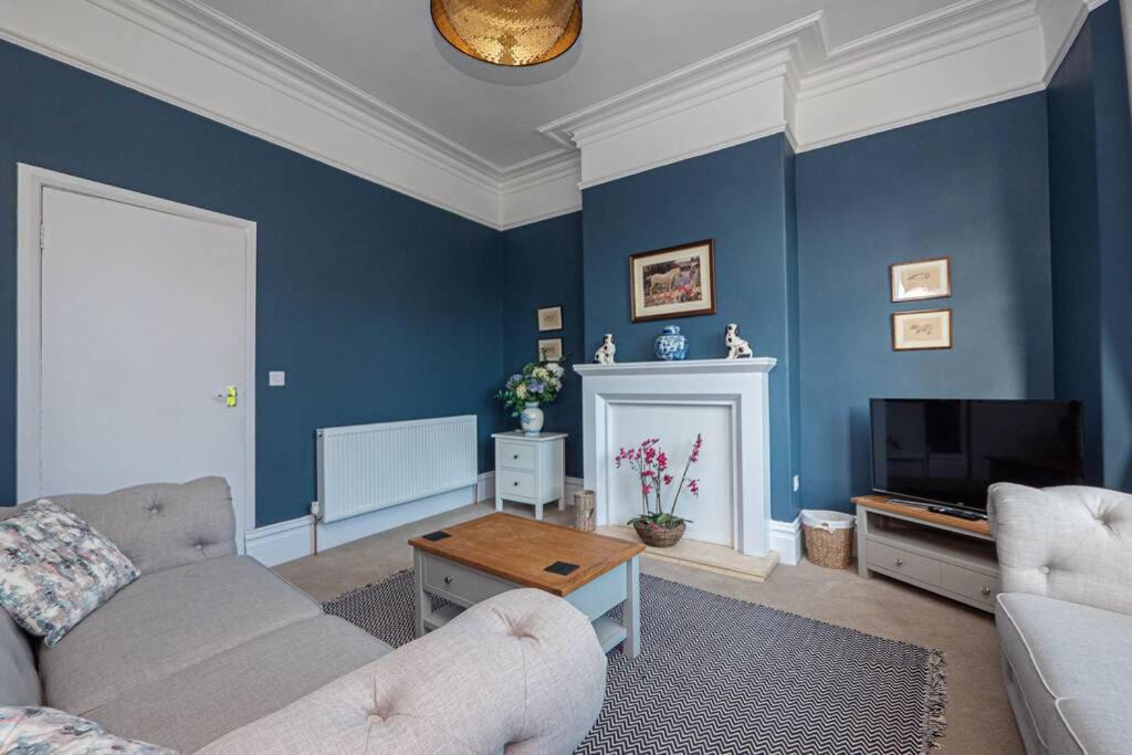 uma sala de estar azul com um sofá e uma televisão em Cliff Garden, Close to Sea em Hornsea