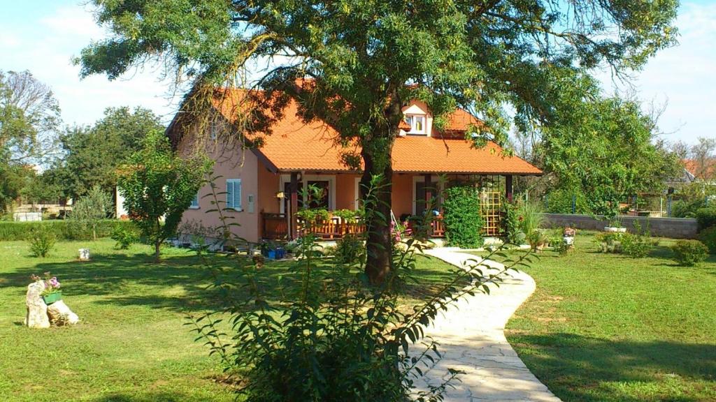 une maison avec un arbre en face d'une cour dans l'établissement Villa Tinov Dvor, à Briševo