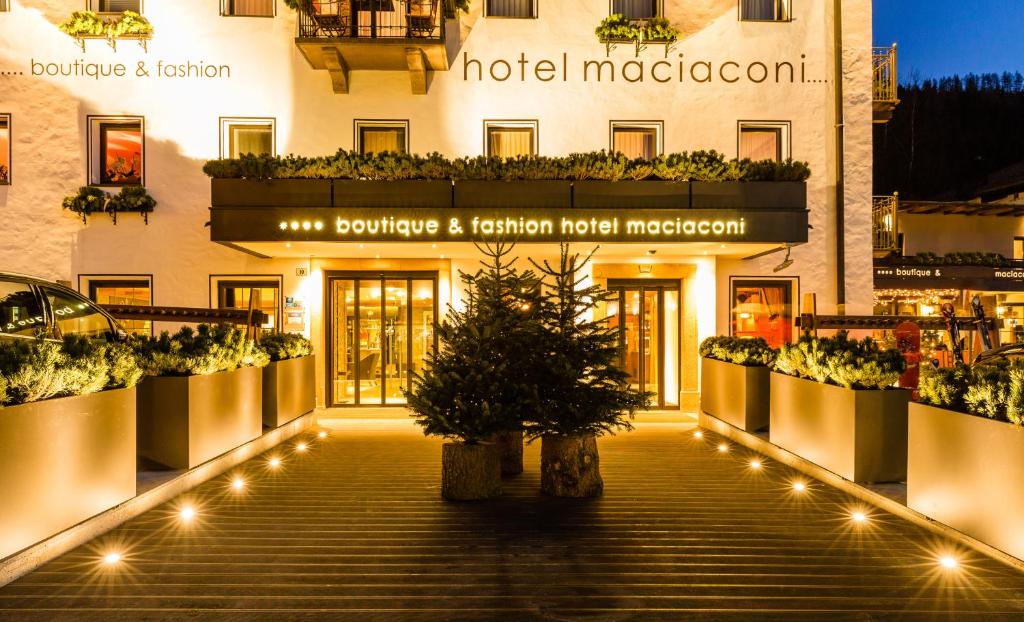 a building with a christmas tree in front of it at Boutique & Fashion Hotel Maciaconi - Gardenahotels in Santa Cristina Gherdëina
