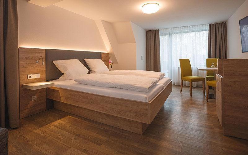 a bedroom with a bed and a table with a chair at Hotel Mediterra in Uhldingen-Mühlhofen