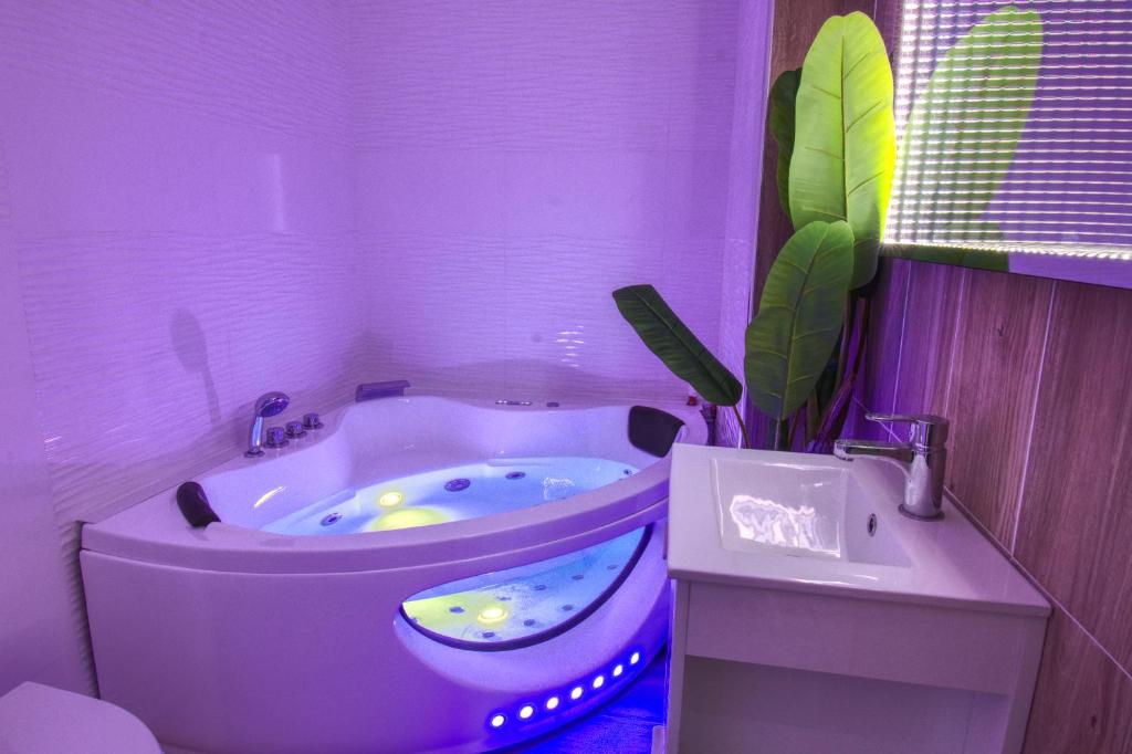 a purple bathroom with a tub and a sink at Appartement Plage et JACUZZI Balnéothérapie Athis Mons in Athis-Mons