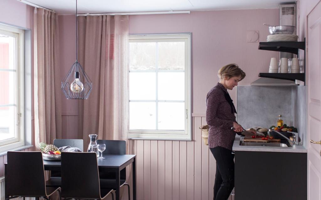 Eine Frau, die in einer Küche steht und Essen zubereitet. in der Unterkunft Stockeboda Gård in Gärsnäs