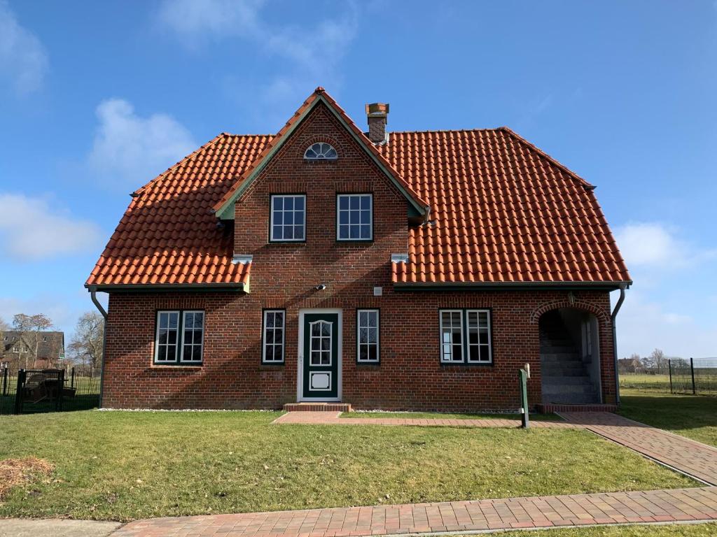 een stenen huis met een oranje dak bij Abendstille, Ferienwohnung für maximal 4 Erwachsene und 2 Kinder in DE FEERJENHUSEN am Haubarg von Vollerwiek in Vollerwiek