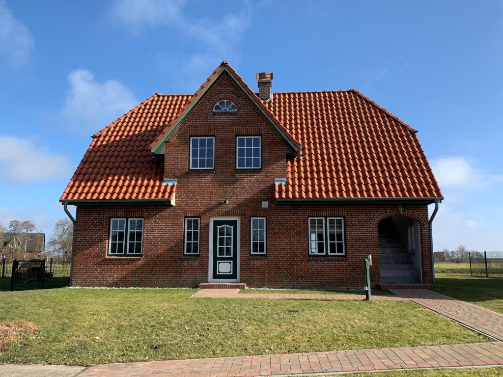 a brick house with an orange roof at Abendstille, Ferienwohnung für maximal 4 Erwachsene und 2 Kinder in DE FEERJENHUSEN am Haubarg von Vollerwiek in Vollerwiek