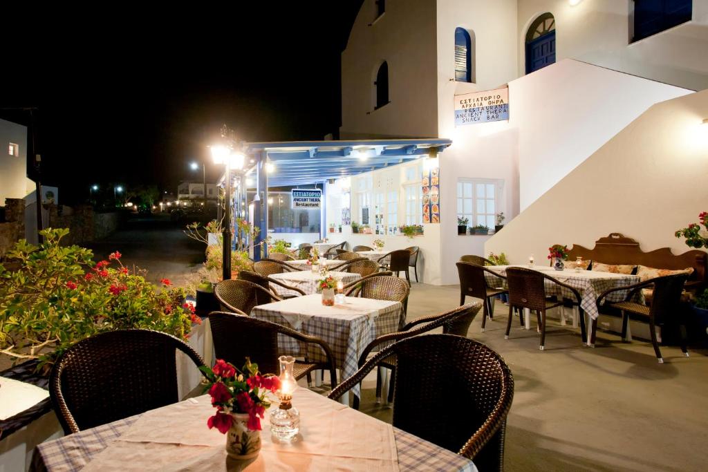 restauracja ze stołami i krzesłami w nocy w obiekcie Ancient Thera Studios w mieście Perissa