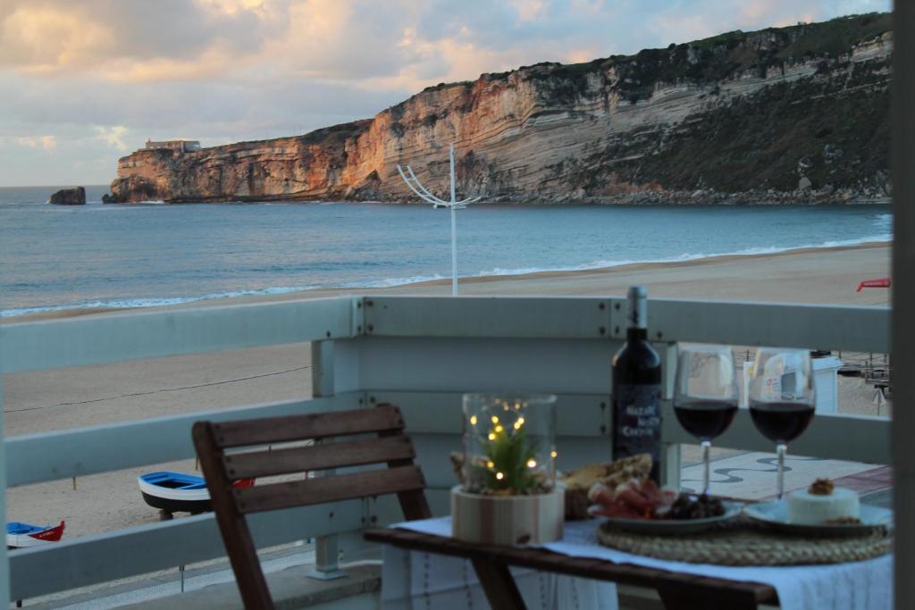 Beachfront Apartment Nazaré في نازاريه: طاولة مع شمعة وكؤوس للنبيذ على الشاطئ