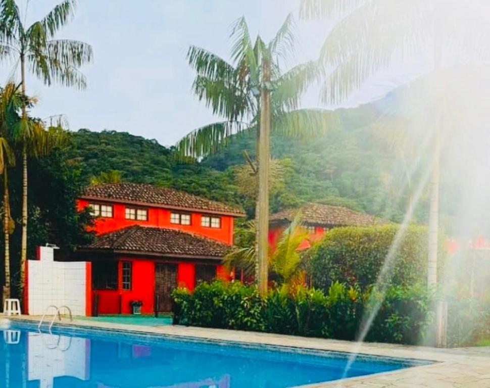 una piscina con una casa roja y palmeras en Chales Terra Pura, en Camburi