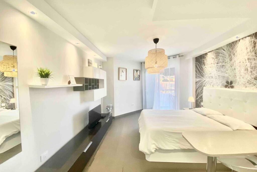 una camera bianca con un grande letto e un tavolo di Vacation Home Studio Los Cristianos ad Arona