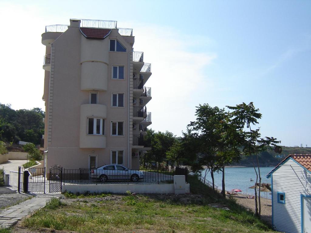 a building with a car parked next to the ocean at Villa Lazuren Bryag 2 in Chernomorets