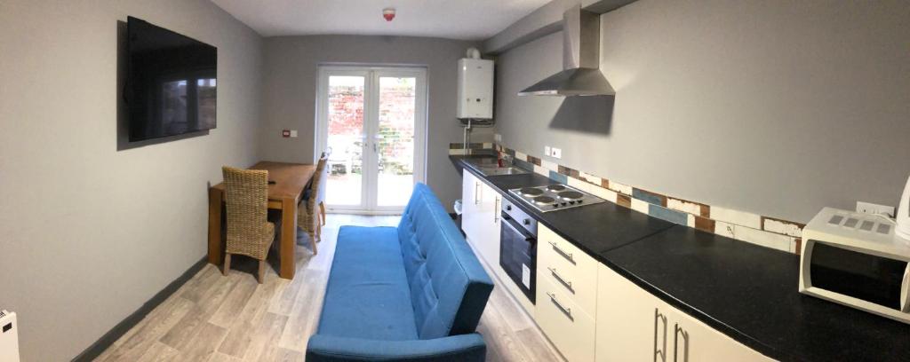 cocina con sofá azul en una habitación en London Gate Lodge - Private En-suite rooms, Kings Lynn, central location en Kings Lynn
