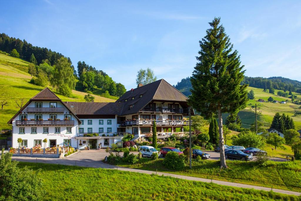 ein Hotel in den Bergen mit parkenden Autos in der Unterkunft Landhaus Langeck in Münstertal