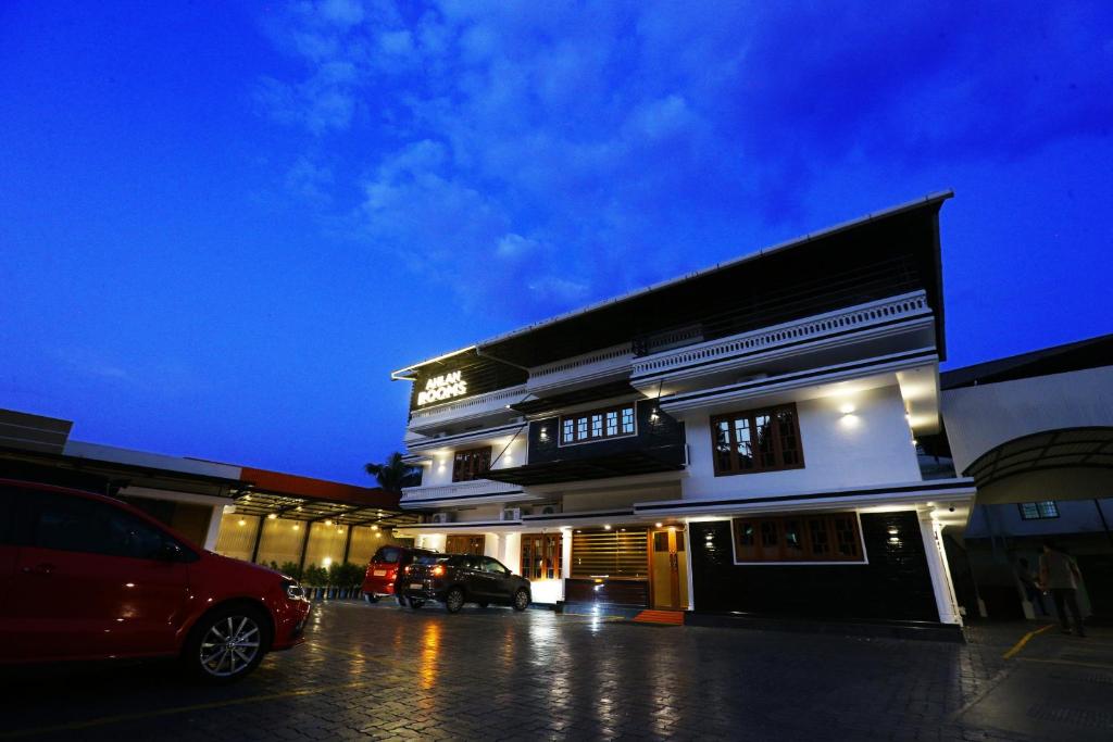 a building with a car parked in a parking lot at Ahlan Luxury Rooms in Cochin