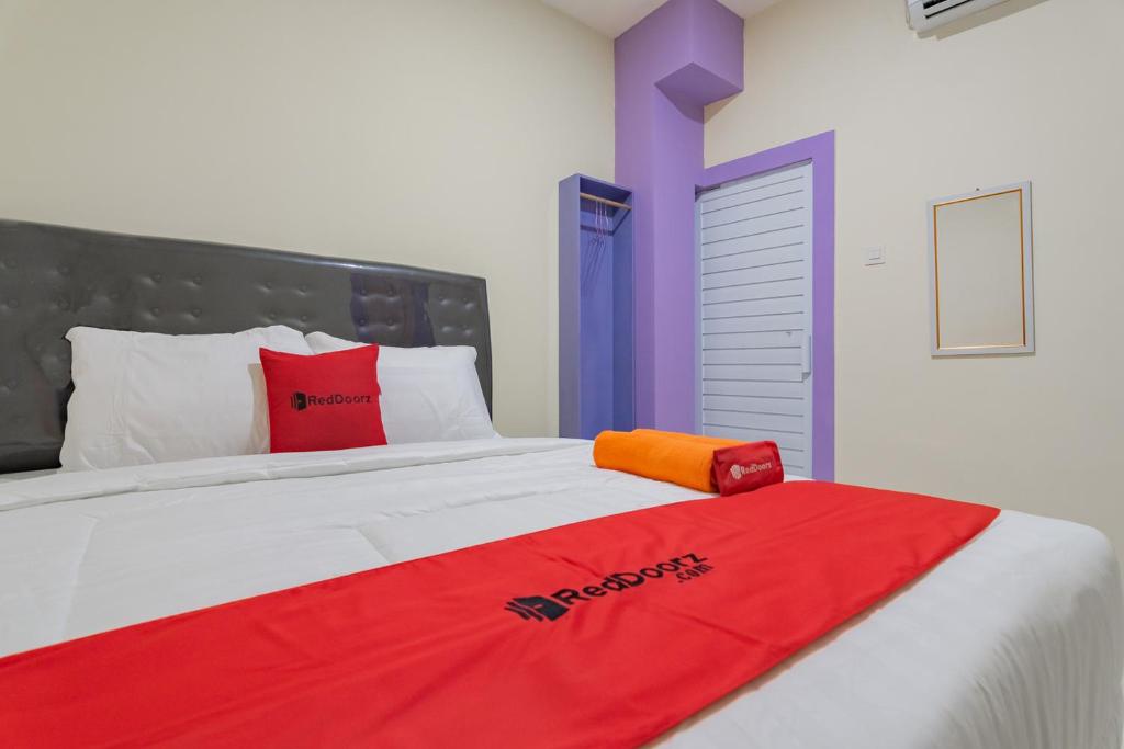 a bed with a red blanket on top of it at RedDoorz near Trans Studio Bandung 3 in Bandung