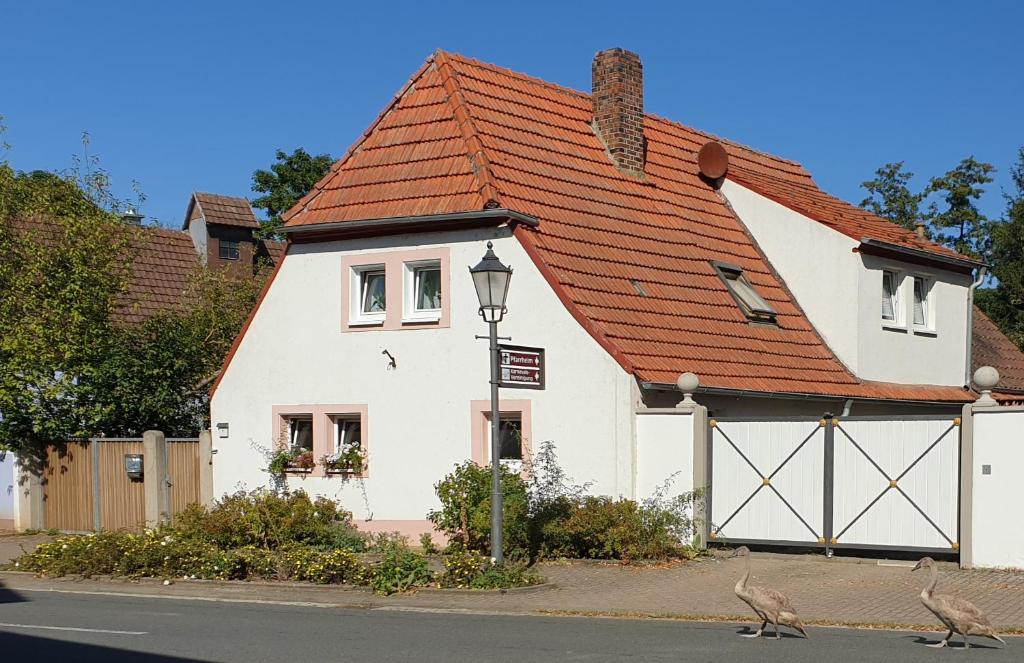 a white house with a red roof and two birds on the street at Unser Obervolkacher Ferienhaus - Hideaway & Gartenoase mit Wohlfühlflair und Herz für Hunde in Volkach