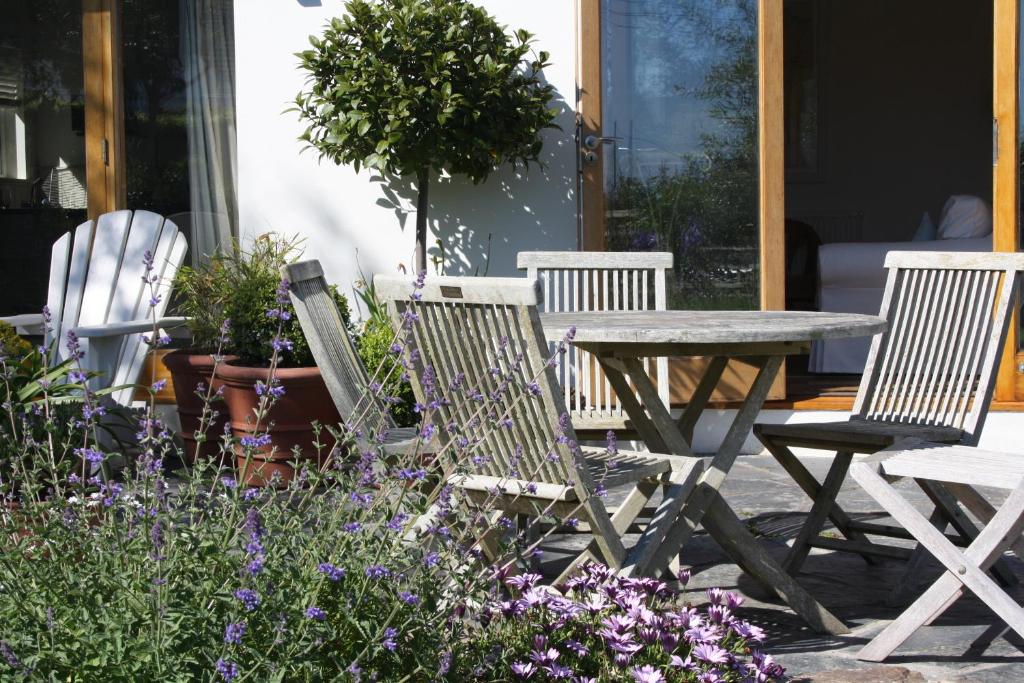 a wooden table and chairs and some purple flowers at Nearwater in Saint Mawes