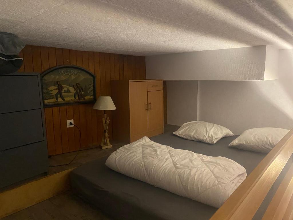 a bedroom with a large bed with white sheets at Studio Belle Hutte 2 in La Bresse